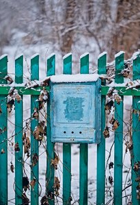 Close up of a mailbox on the street with blue fence